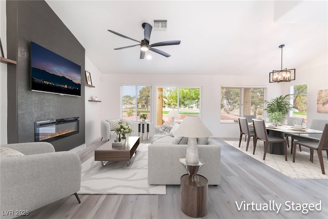 2553 Showcase Dr, Las Vegas, NV 89134 - living room with lofted ceiling, wood finished floors, a large fireplace, a chandelier, and a ceiling fan