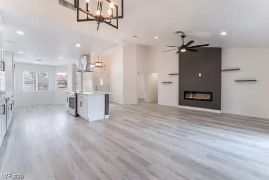 2553 Showcase Dr, Las Vegas, NV 89134 - unfurnished living room featuring a chandelier, recessed lighting, light wood-type flooring, a glass covered fireplace, and ceiling fan