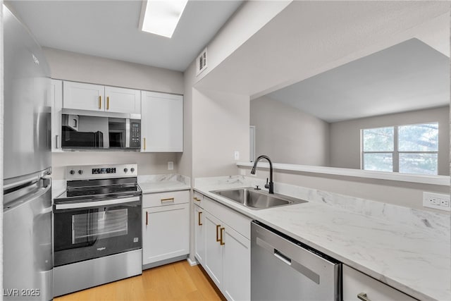1150 N Buffalo Dr Unit 2025, Las Vegas, NV 89128 - kitchen featuring appliances with stainless steel finishes, white cabinets, light wood-style floors, and light stone counters