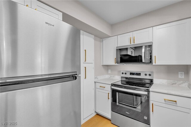1150 N Buffalo Dr Unit 2025, Las Vegas, NV 89128 - kitchen featuring appliances with stainless steel finishes, white cabinetry, light wood-style floors, and light stone counters