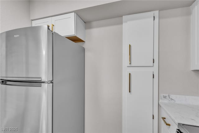 1150 N Buffalo Dr Unit 2025, Las Vegas, NV 89128 - kitchen with freestanding refrigerator, white cabinets, light stone countertops, and stove