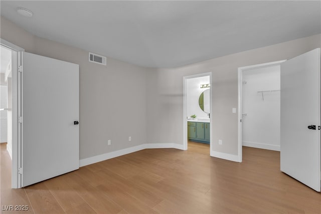 1150 N Buffalo Dr Unit 2025, Las Vegas, NV 89128 - unfurnished bedroom with light wood-style flooring, a spacious closet, connected bathroom, and a closet