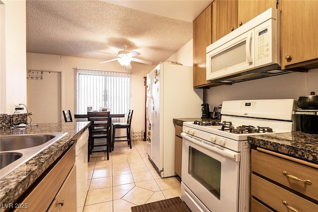 3890 Lancome St, Las Vegas, NV 89115 - kitchen with white appliances, ceiling fan, light tile patterned flooring, brown cabinetry, and a textured ceiling