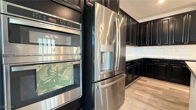 754 Agate Hills St, Las Vegas, NV 89138 - kitchen featuring stainless steel appliances, a chandelier, light stone countertops, decorative backsplash, and light wood-style flooring