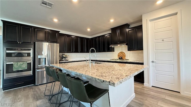 754 Agate Hills St, Las Vegas, NV 89138 - kitchen featuring appliances with stainless steel finishes, a sink, light wood-style floors, decorative backsplash, and light stone counters