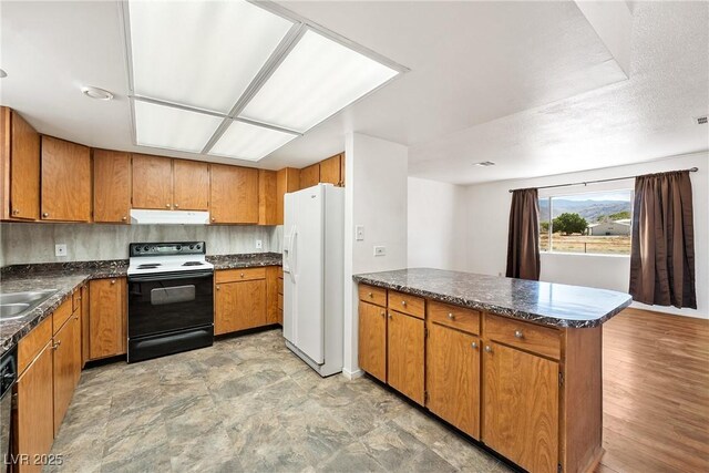 2440 Homestead Rd, Pahrump, NV 89048 - kitchen with range with electric stovetop, white fridge with ice dispenser, under cabinet range hood, and brown cabinets