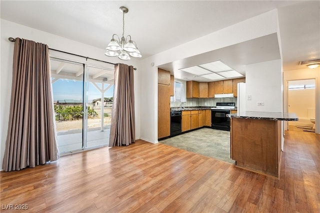 2440 Homestead Rd, Pahrump, NV 89048 - kitchen with range, black dishwasher, light wood-style floors, brown cabinetry, and a chandelier