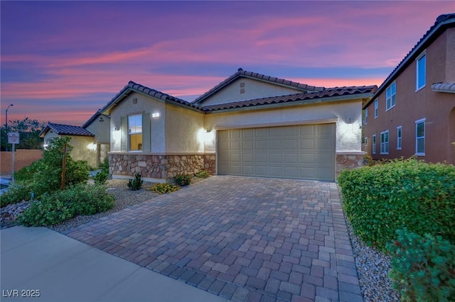 708 Kibbey St, Las Vegas, NV 89178 - mediterranean / spanish house featuring stone siding, stucco siding, decorative driveway, and an attached garage