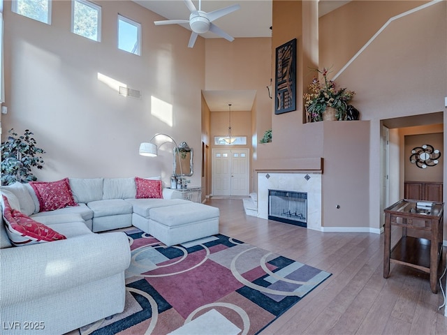 2521 Seascape Dr, Las Vegas, NV 89128 - living room with a high ceiling, a ceiling fan, wood finished floors, a tiled fireplace, and baseboards