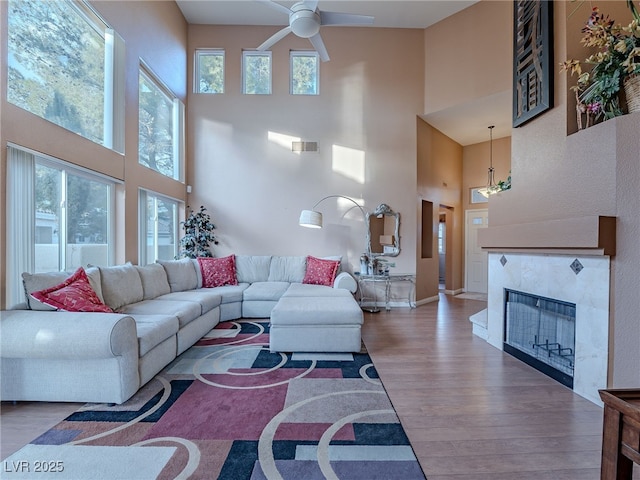 2521 Seascape Dr, Las Vegas, NV 89128 - living area with a towering ceiling, a ceiling fan, healthy amount of natural light, wood finished floors, and a premium fireplace