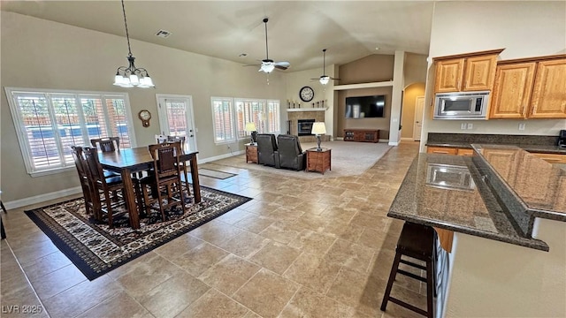 1361 Moose St, Pahrump, NV 89048 - dining space featuring ceiling fan, healthy amount of natural light, a tile fireplace, baseboards, and high vaulted ceiling