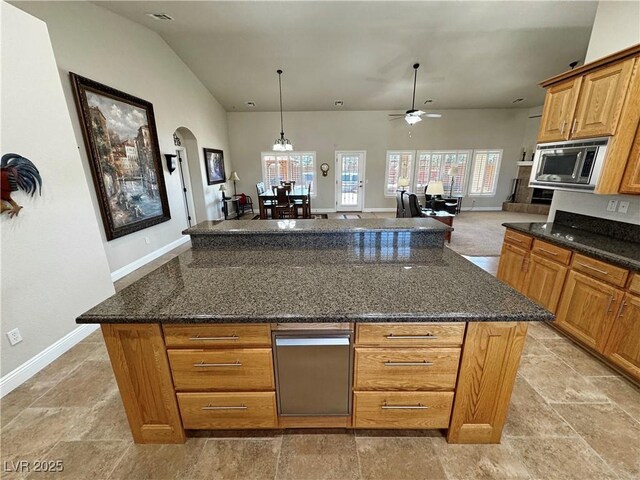 1361 Moose St, Pahrump, NV 89048 - kitchen featuring stainless steel microwave, baseboards, light stone finish flooring, dark stone counters, and arched walkways
