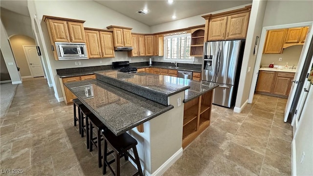 1361 Moose St, Pahrump, NV 89048 - kitchen with open shelves, stainless steel appliances, arched walkways, a kitchen island, and under cabinet range hood