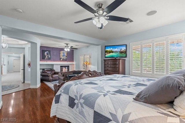 7001 Via Locanda Ave, Las Vegas, NV 89131 - bedroom with wood-type flooring, baseboards, ceiling fan, and a glass covered fireplace