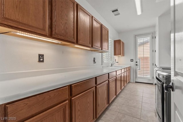 7001 Via Locanda Ave, Las Vegas, NV 89131 - kitchen featuring stainless steel stove, brown cabinets, light countertops, and light tile patterned flooring