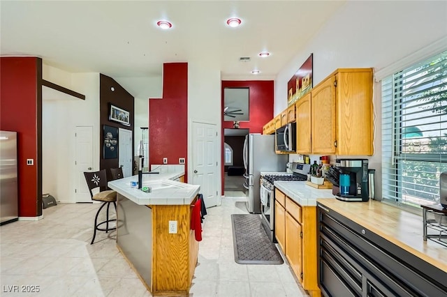 1905 Dakota Hills Ave, Las Vegas, NV 89123 - kitchen with stainless steel appliances, a kitchen breakfast bar, tile counters, and a peninsula