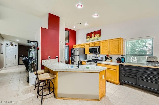 1905 Dakota Hills Ave, Las Vegas, NV 89123 - kitchen with appliances with stainless steel finishes, tile countertops, a kitchen breakfast bar, a peninsula, and recessed lighting
