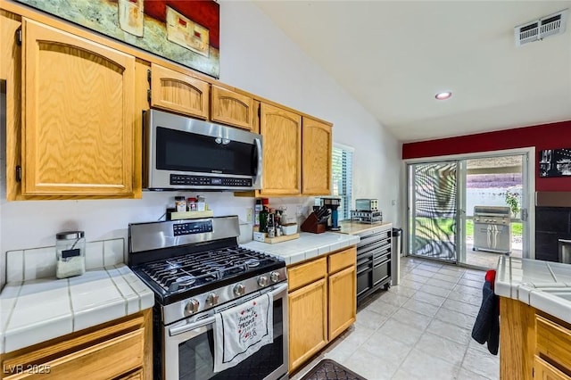 1905 Dakota Hills Ave, Las Vegas, NV 89123 - kitchen featuring stainless steel appliances, tile counters, vaulted ceiling, light tile patterned floors, and recessed lighting