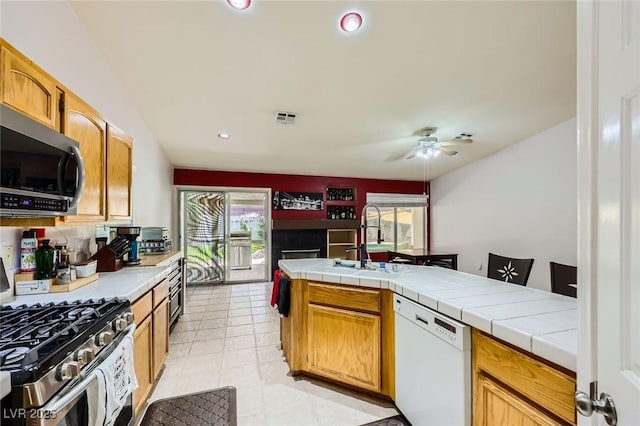 1905 Dakota Hills Ave, Las Vegas, NV 89123 - kitchen featuring appliances with stainless steel finishes, a ceiling fan, tile countertops, light tile patterned flooring, and recessed lighting
