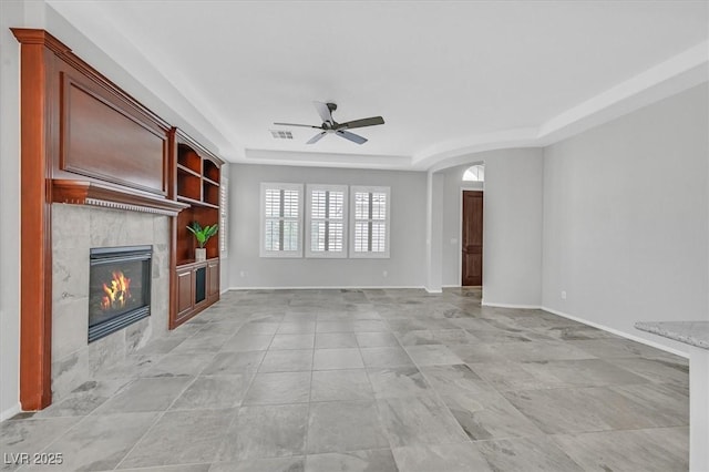 4020 Recktenwall Ave, North Las Vegas, NV 89081 - unfurnished living room with a ceiling fan, a tile fireplace, a tray ceiling, arched walkways, and baseboards