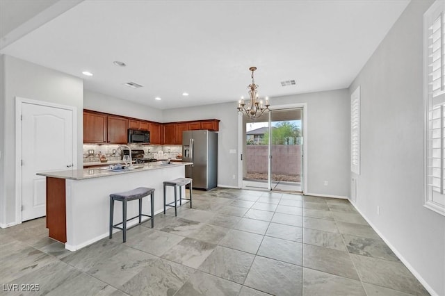4020 Recktenwall Ave, North Las Vegas, NV 89081 - kitchen with stainless steel fridge, black microwave, a chandelier, a breakfast bar, and light countertops