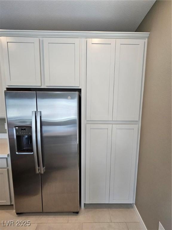 289 Aravalli Crest St, Henderson, NV 89015 - kitchen with stainless steel refrigerator with ice dispenser, light tile patterned floors, baseboards, light countertops, and white cabinets