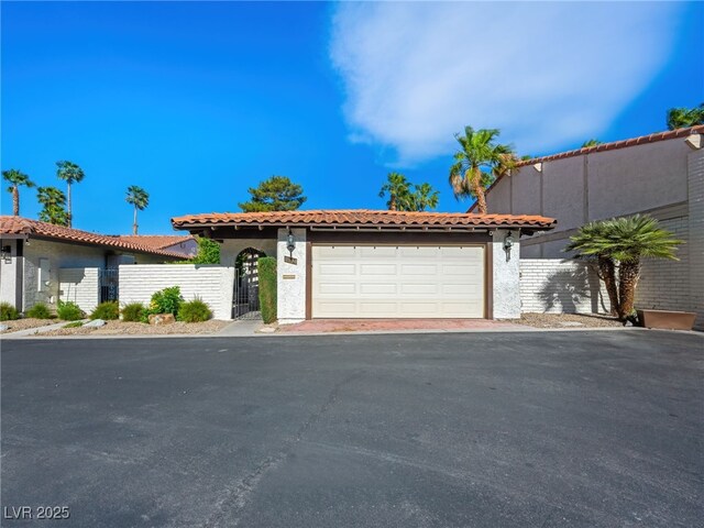 2104 Plaza De La Candela, Las Vegas, NV 89102 - mediterranean / spanish-style house with an attached garage, stucco siding, a gate, and driveway