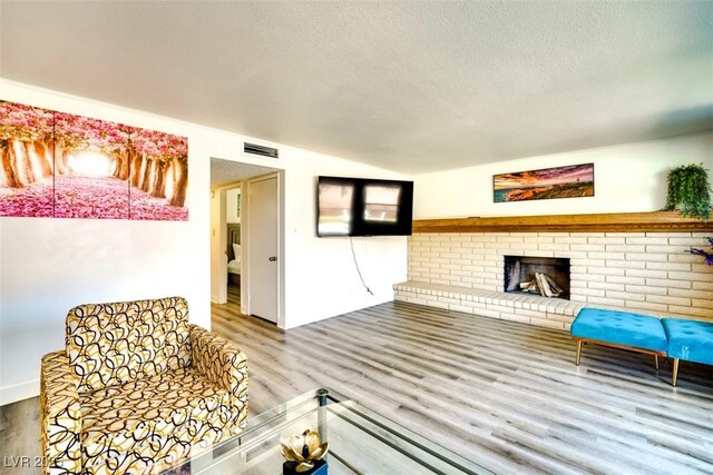 864 E Eldorado Ln, Las Vegas, NV 89123 - unfurnished living room featuring wood finished floors, a textured ceiling, a fireplace, and vaulted ceiling