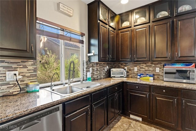 6714 Flamenco Ct, Las Vegas, NV 89139 - kitchen with appliances with stainless steel finishes, tasteful backsplash, dark brown cabinets, light stone counters, and glass insert cabinets