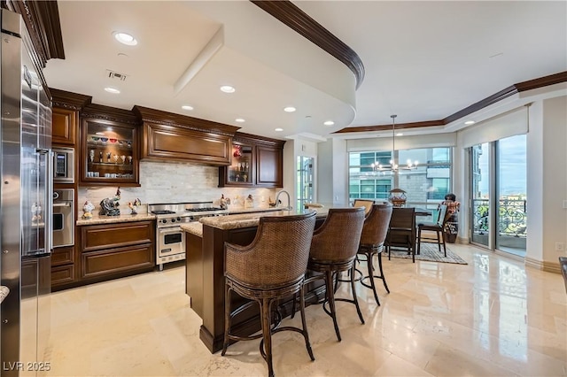 9103 Alta Dr Unit 407, Las Vegas, NV 89145 - kitchen featuring premium appliances, crown molding, decorative backsplash, a kitchen breakfast bar, and light stone countertops