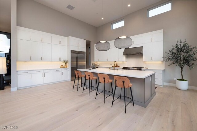 10781 Agate Cliffs Ave, Las Vegas, NV 89135 - kitchen featuring built in refrigerator, a towering ceiling, extractor fan, a breakfast bar area, and light wood-type flooring