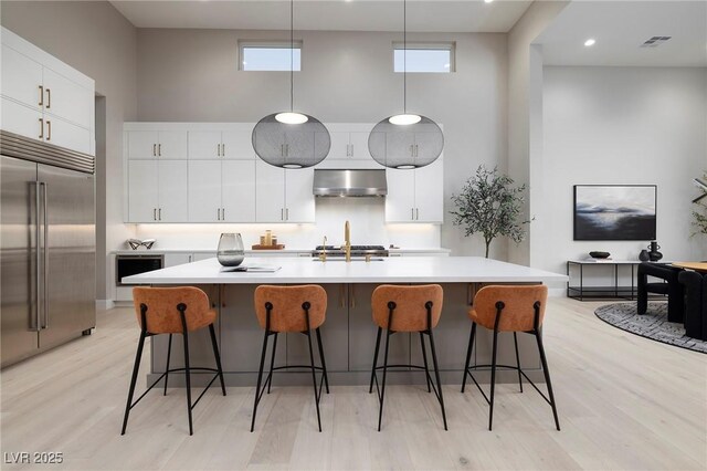 10781 Agate Cliffs Ave, Las Vegas, NV 89135 - kitchen with exhaust hood, stainless steel built in fridge, a high ceiling, light countertops, and light wood-style flooring