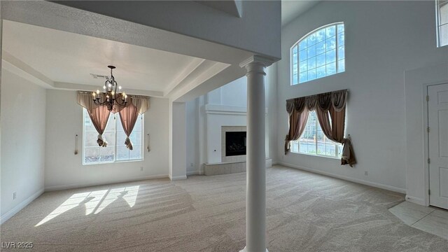 10066 Golden Bluff Ave, Las Vegas, NV 89148 - unfurnished living room featuring carpet, a chandelier, a fireplace, baseboards, and a towering ceiling