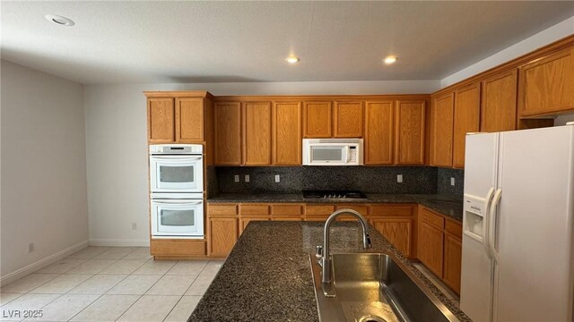 10066 Golden Bluff Ave, Las Vegas, NV 89148 - kitchen with white appliances, brown cabinets, baseboards, a sink, and recessed lighting