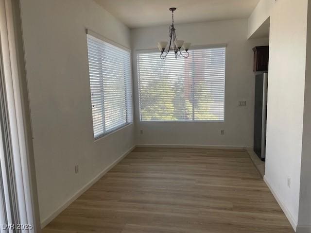 15 E Agate Ave Unit 202, Las Vegas, NV 89123 - unfurnished dining area with plenty of natural light, a chandelier, light wood finished floors, and baseboards