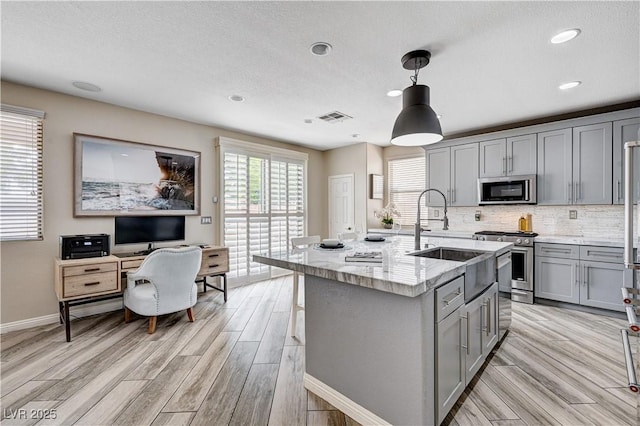 4308 Desert Haven Ave, North Las Vegas, NV 89085 - kitchen with gray cabinetry, appliances with stainless steel finishes, a sink, light stone countertops, and light wood-type flooring