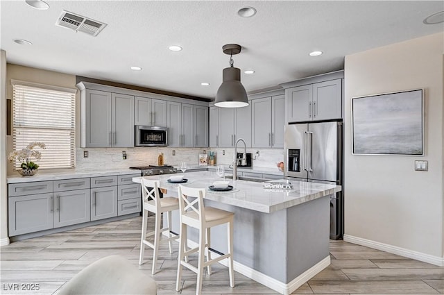 4308 Desert Haven Ave, North Las Vegas, NV 89085 - kitchen featuring gray cabinets, appliances with stainless steel finishes, backsplash, light wood-style floors, and baseboards