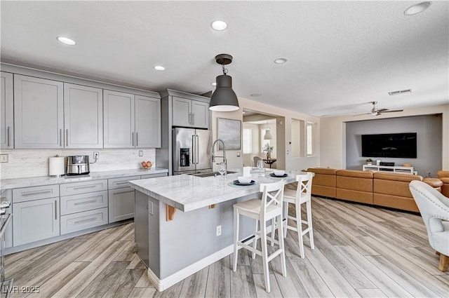 4308 Desert Haven Ave, North Las Vegas, NV 89085 - kitchen featuring gray cabinets, stainless steel fridge, ceiling fan, light wood-style floors, and a kitchen bar