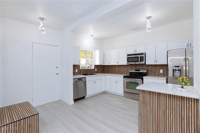 3008 Lawndale St, Las Vegas, NV 89121 - kitchen featuring stainless steel appliances, white cabinets, a sink, light stone countertops, and a peninsula