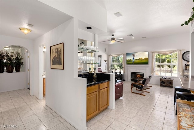 5104 Burr Oak Dr, Las Vegas, NV 89130 - kitchen featuring ceiling fan, light tile patterned flooring, a lit fireplace, dark countertops, and open floor plan