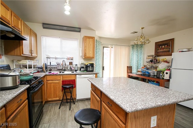 6520 Blooming Sun Ct, Las Vegas, NV 89142 - kitchen featuring white appliances, light wood-type flooring, a chandelier, and under cabinet range hood