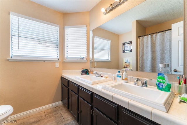 6529 Hartwood Rd, Las Vegas, NV 89108 - bathroom with double vanity, toilet, baseboards, and tile patterned floors