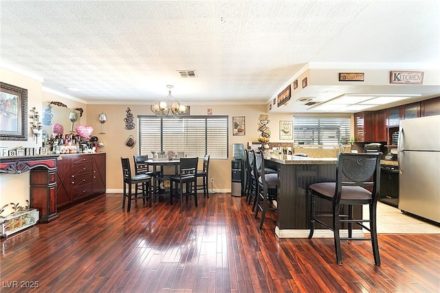 6529 Hartwood Rd, Las Vegas, NV 89108 - kitchen with freestanding refrigerator, a chandelier, a breakfast bar area, a peninsula, and wood-type flooring