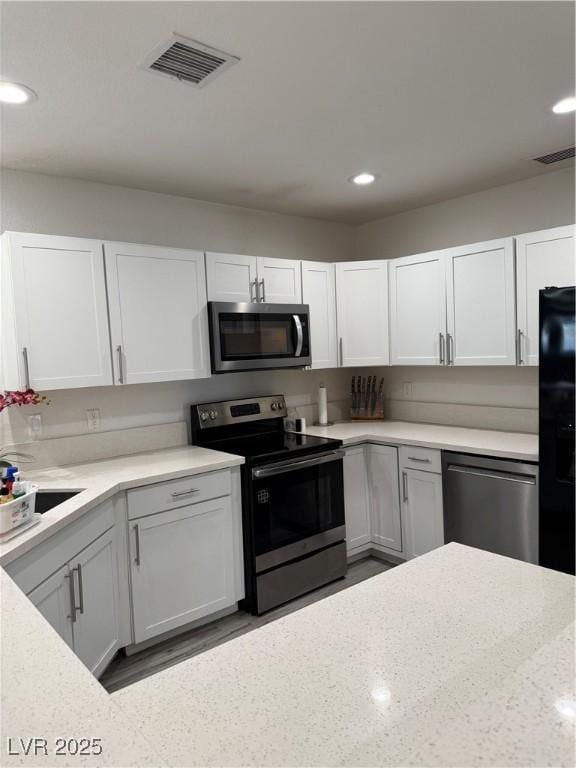 621 S 9th St, Las Vegas, NV 89101 - kitchen with appliances with stainless steel finishes, white cabinets, recessed lighting, and light stone counters