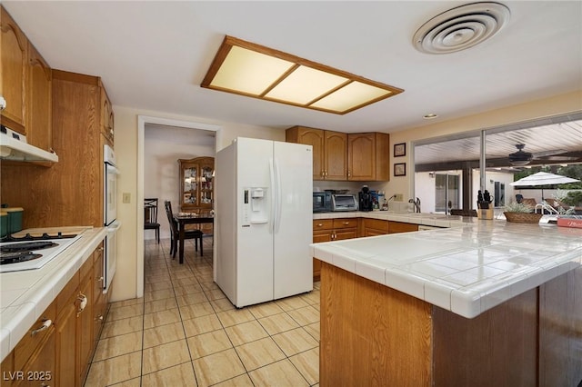 4219 E Pinecrest Cir, Las Vegas, NV 89121 - kitchen with white appliances, tile counters, a peninsula, and brown cabinets