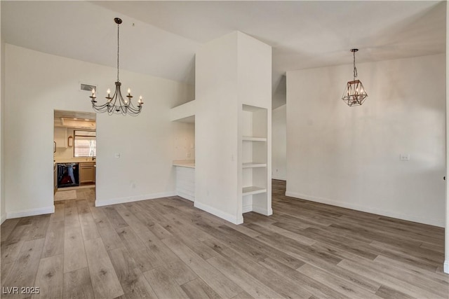 7417 Radville Dr, Las Vegas, NV 89129 - unfurnished dining area featuring a chandelier, light wood-type flooring, built in features, baseboards, and high vaulted ceiling
