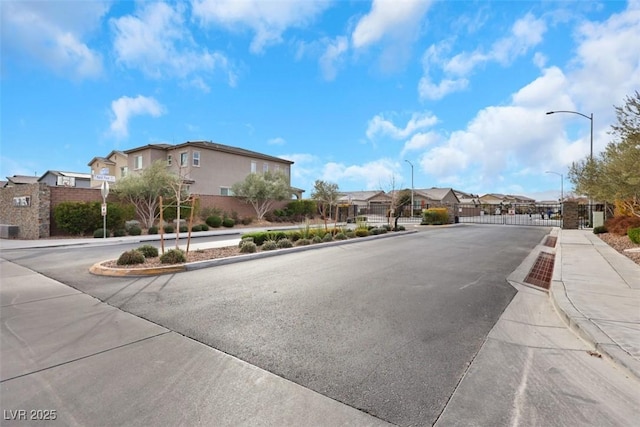 7115 Calvert Cliffs St, North Las Vegas, NV 89084 - view of asphalt street with sidewalks, a residential view, curbs, street lights, and a gate