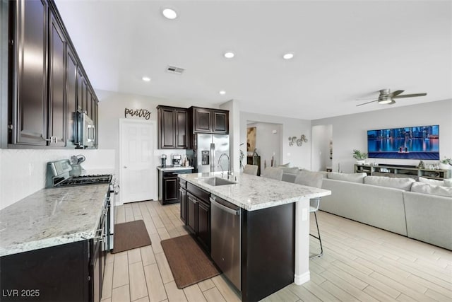 7115 Calvert Cliffs St, North Las Vegas, NV 89084 - kitchen with appliances with stainless steel finishes, open floor plan, a sink, ceiling fan, and a kitchen bar