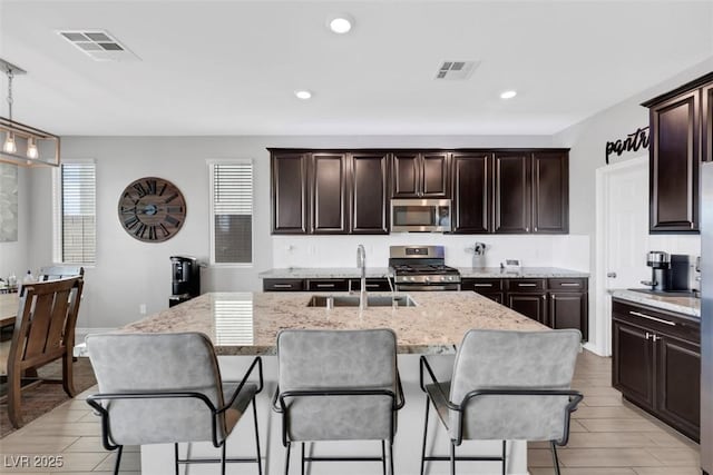 7115 Calvert Cliffs St, North Las Vegas, NV 89084 - kitchen with appliances with stainless steel finishes, a sink, light stone counters, a kitchen bar, and recessed lighting