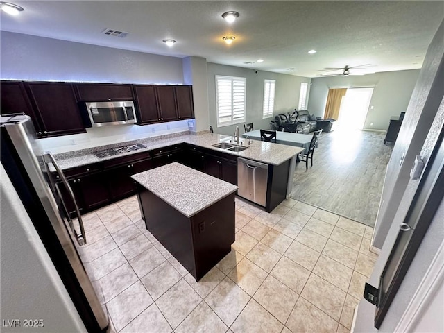 7035 Thistle Ridge St, Las Vegas, NV 89166 - kitchen featuring appliances with stainless steel finishes, a sink, a kitchen island, ceiling fan, and light tile patterned flooring